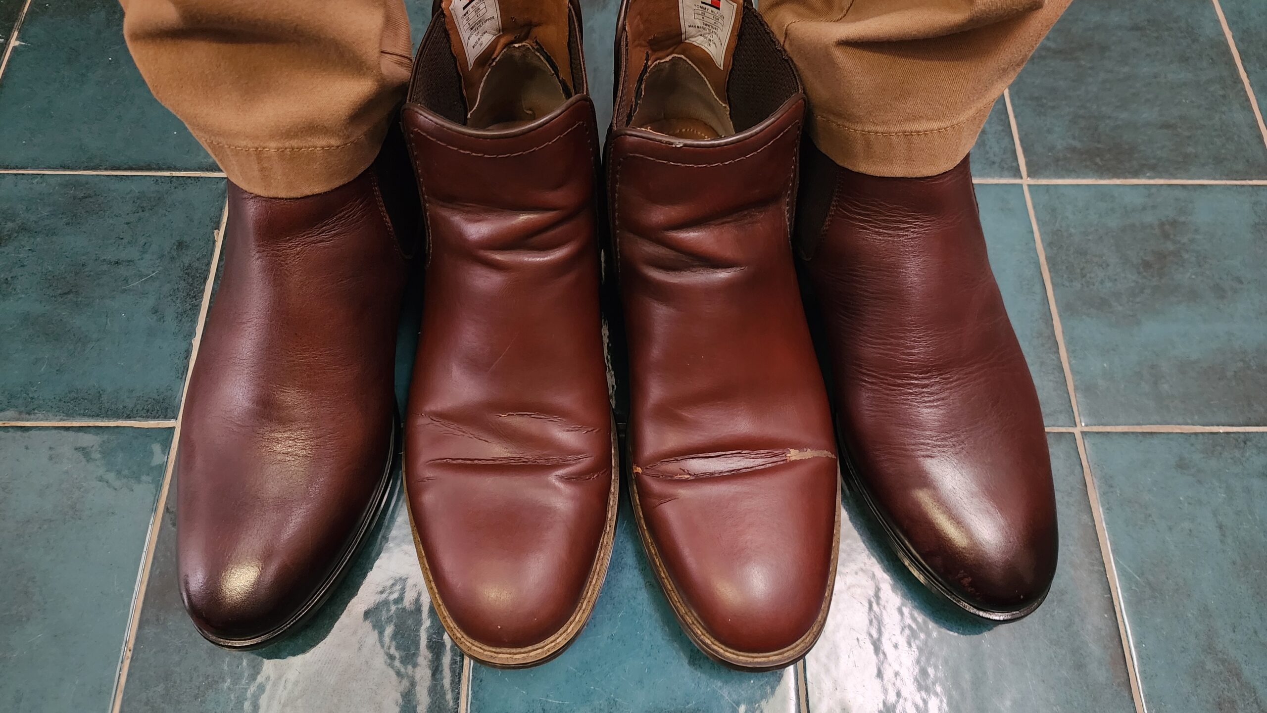 Cận cảnh KNAR Chelsea Boot đặt cạnh Chelsea Tommy Hilfiger có lớp bề mặt bị nứt tại vùng gập